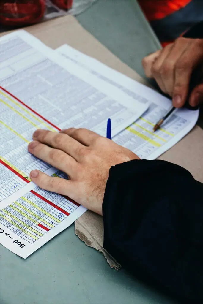 Gros plan sur des mains analysant un tableau de suivi, illustrant la prise en charge administrative des processus de tri.